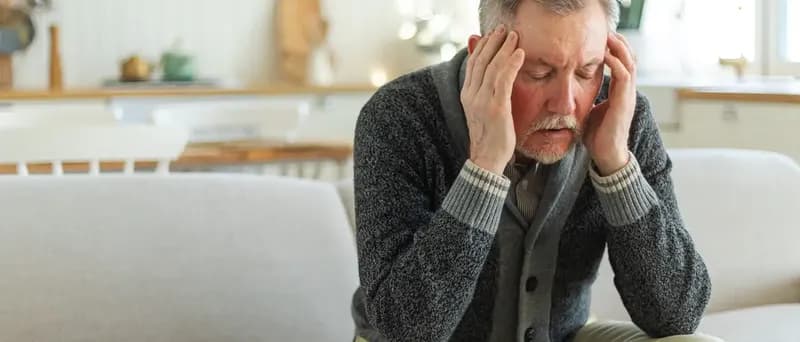 Elderly man with hands on head
