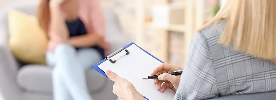 Woman from behind taking notes during a therapeutic session.