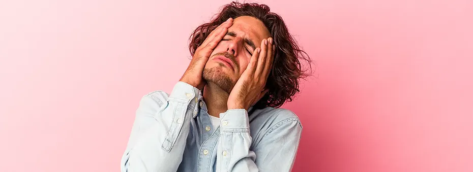Young man lamenting with his hands on his face.